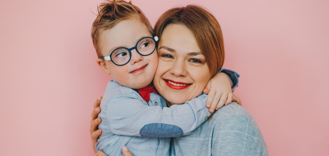Zespół angelmana - zdjęcie ilustrujące na którym jest mama przytulająca chłopczyka w okularach