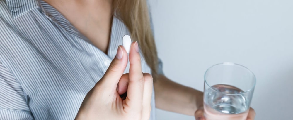 Kobieta przyjmująca tabletkę - leki na refluks - nowafarmacja.pl