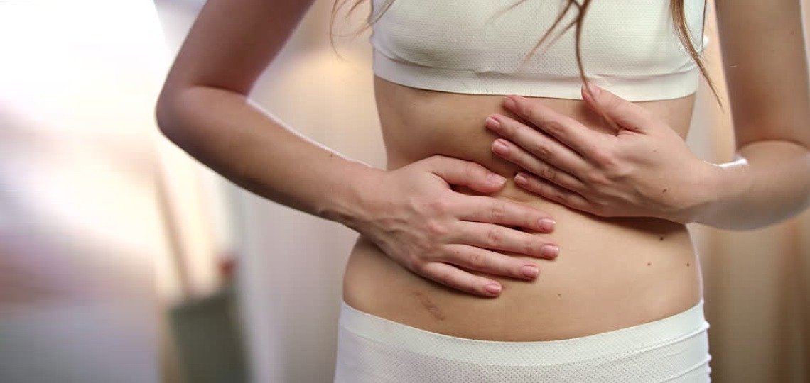 Kobieta łapiąca się za brzuch - objawy helicobacter pylori - nowafarmacja.pl