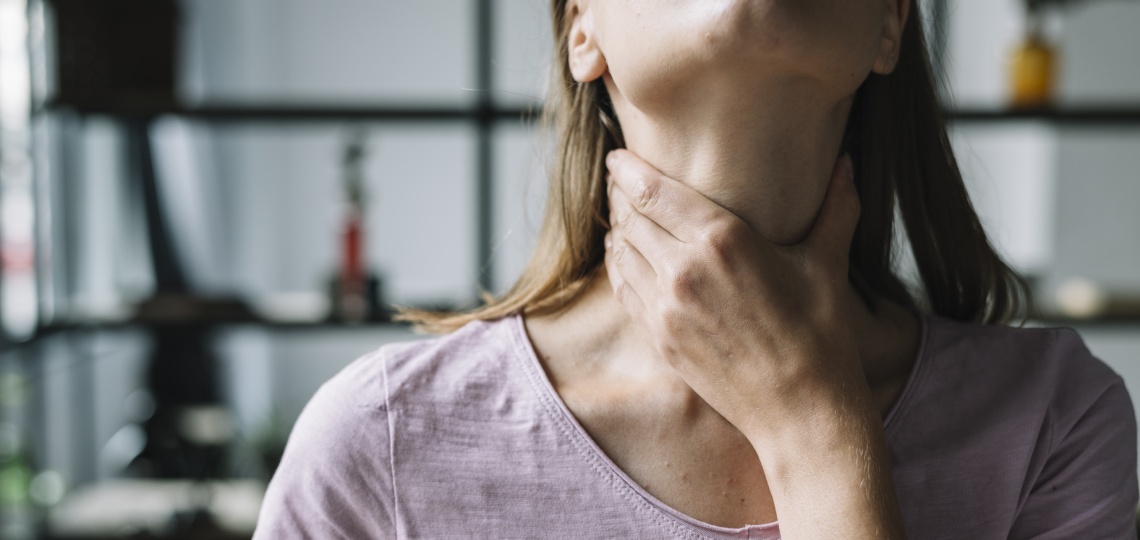 Kobieta trzymająca się za szyję - Tarczyca a wypadanie włosów - nowafarmacja.pl